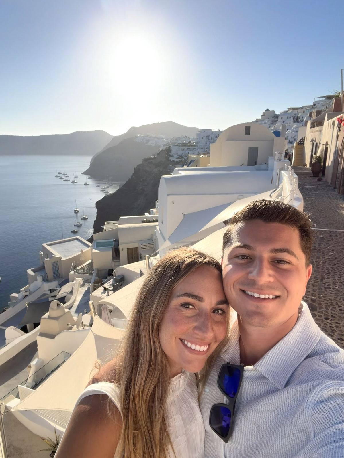Pete and Cassie taking a selfie above the white cliffside village of Oia in Santorini