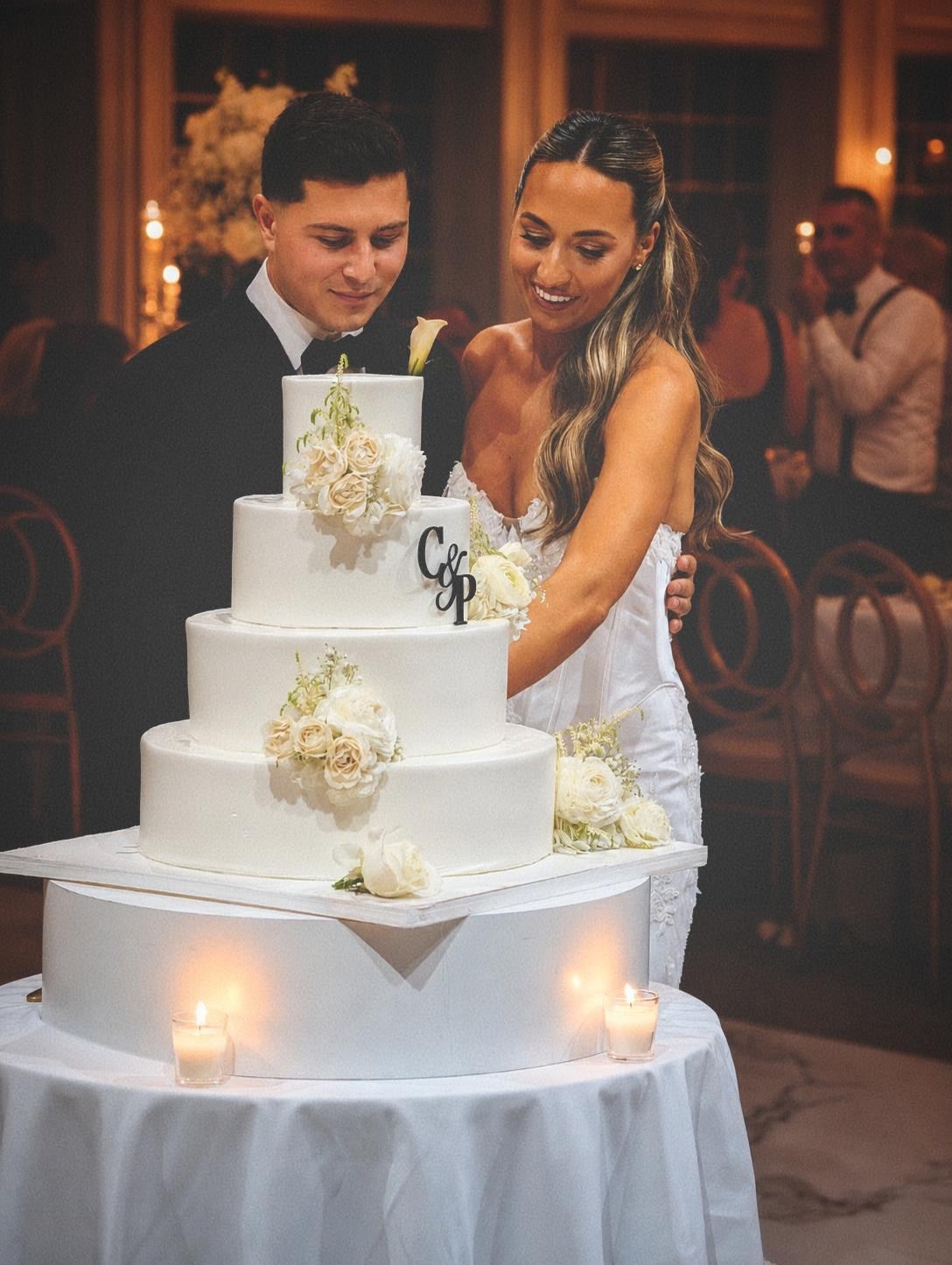 Pete and Cassie cutting their four-tier wedding cake